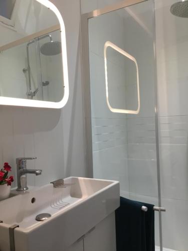 a white bathroom with a sink and a mirror at La Prévôté in Moissac
