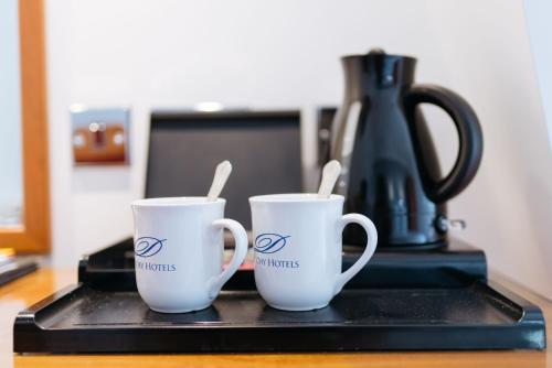 two white coffee mugs sitting on a black tray at The Queens Hotel in Paignton