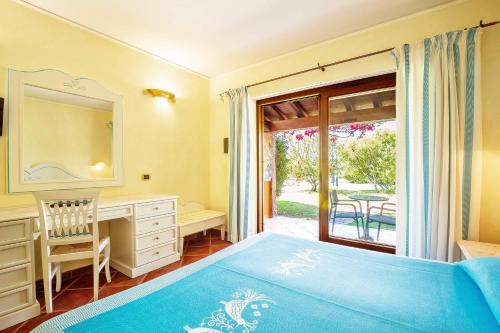 a bedroom with a bed and a desk and a window at Hotel Club Saraceno - Bovis Hotels in Àrbatax