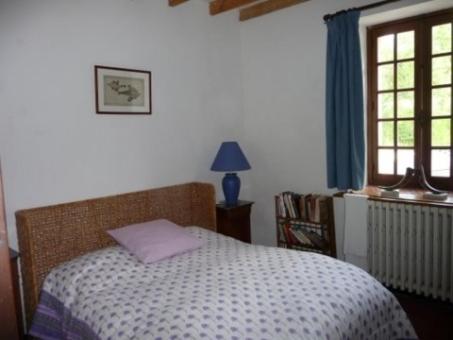 a bedroom with a bed with a purple pillow on it at Gite Des Etangs in Paulnay