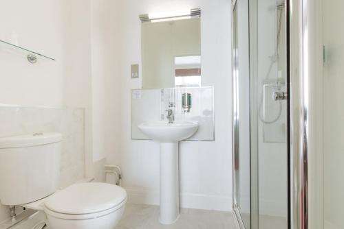 een witte badkamer met een toilet en een wastafel bij The Queens Hotel in Paignton