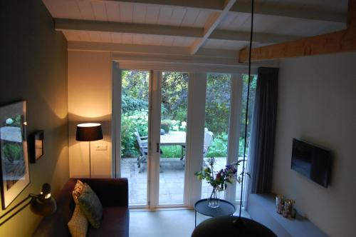 een woonkamer met een bank en een glazen schuifdeur bij "Buitendijks Genieten" in Dreumel