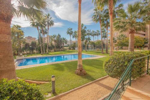 ein Schwimmbad in einem Park mit Palmen in der Unterkunft Alborada Golf 3BD in Albir