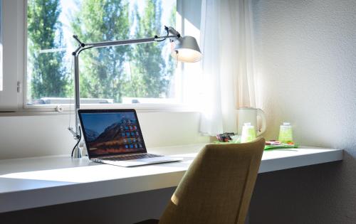 a laptop computer sitting on a desk next to a window at Campanile Beaune in Beaune