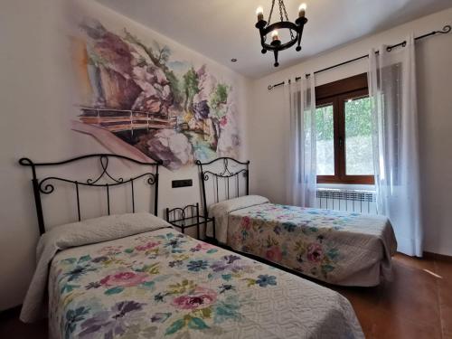 - une chambre avec 2 lits et un tableau mural dans l'établissement Casa Rural Ruiz Hernando, à Villanueva del Arzobispo