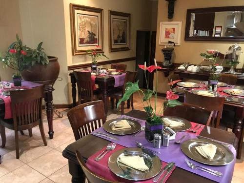 een eetkamer met tafels en stoelen met paarse tafelinstellingen bij Le Cozmo Guesthouse in Johannesburg
