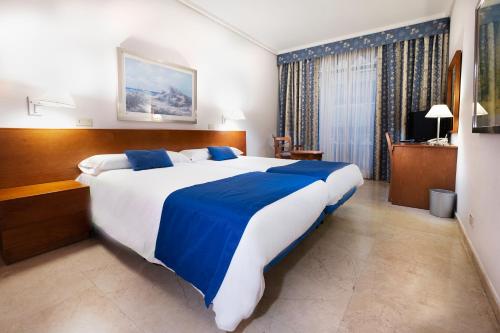 a bedroom with a large bed with blue and white sheets at Hotel Concorde in Las Palmas de Gran Canaria