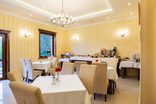 ミエルノにあるPensjonat Solarの白いテーブルと椅子、シャンデリアのあるレストラン