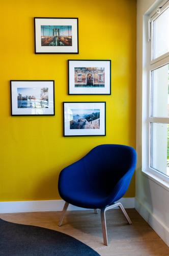 a blue chair in a room with a yellow wall at Campanile Beaune in Beaune