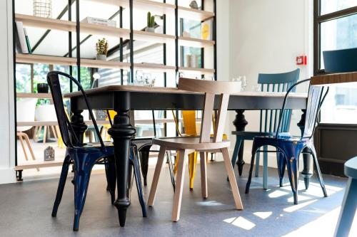 a table and chairs in a room with windows at Campanile Beaune in Beaune