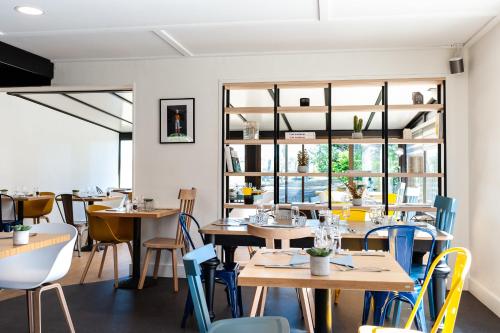 a restaurant with wooden tables and blue chairs at Campanile Beaune in Beaune