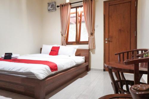 - une chambre avec un lit, une table et une fenêtre dans l'établissement RedDoorz Syariah near Exit Tol Malang, à Malang