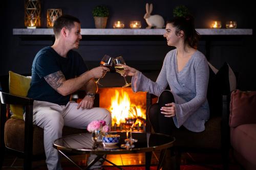 a man and woman drinking wine in front of a fire at Best Western Sanctuary Inn in Tamworth