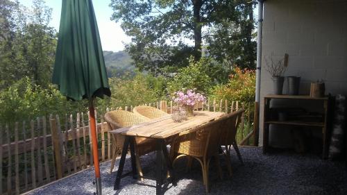 a wooden table with chairs and a green umbrella at vakantieverblijf Nature in Stavelot