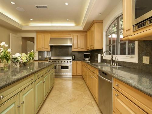 a large kitchen with wooden cabinets and stainless steel appliances at Villa Teresita - Beautifully gated Mediterranean estate in Los Angeles