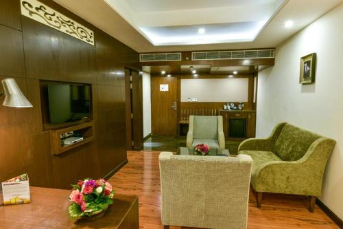 a living room with two chairs and a television at Souvenir Jaipur in Jaipur