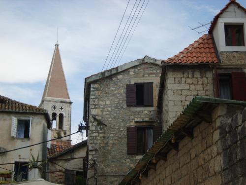 an old stone building with a church steeple in the background at Rooms Roso in Trogir