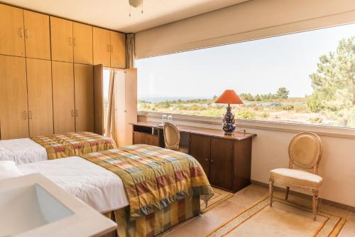 a hotel room with two beds and a large window at Entre Mar e Mar in Aldeia do Meco