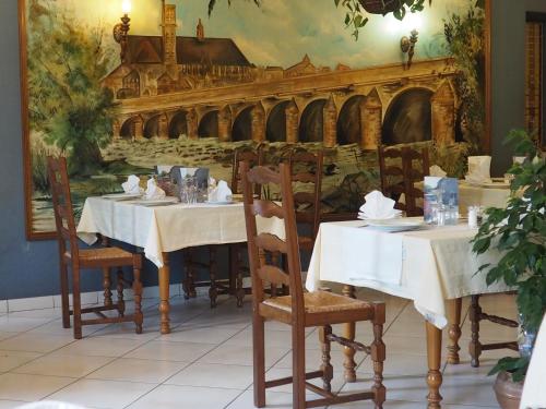 a restaurant with two tables and a painting of a bridge at Hôtel Restaurant La Manse in Dornecy