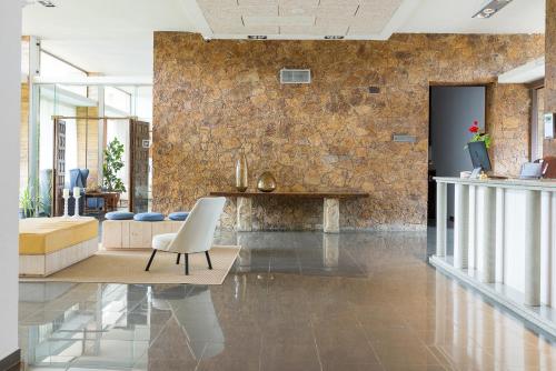 a living room with a white chair and a stone wall at Hotel Alga in Calella de Palafrugell