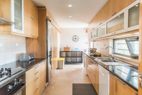a large kitchen with wooden cabinets and a sink at Entre Mar e Mar in Aldeia do Meco