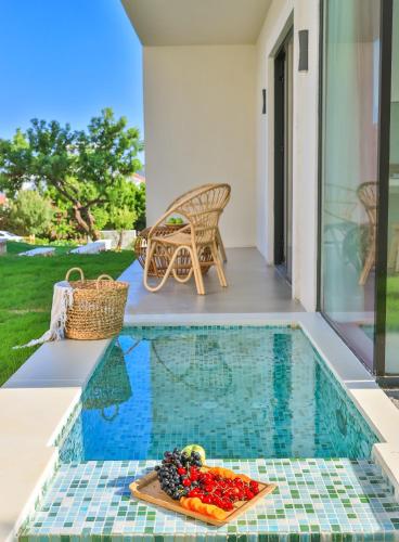 a tray of fruit on a table next to a swimming pool at Carruba Boutique Hotel in Kas
