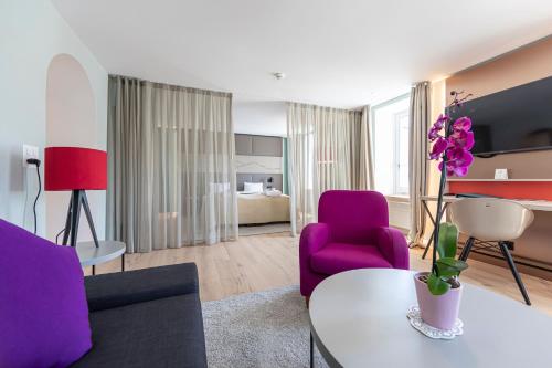 a living room with purple chairs and a table at Hotel Rosatsch in Pontresina