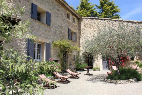 a stone building with chairs and a table in a courtyard at Les Logis de Paban in Crestet