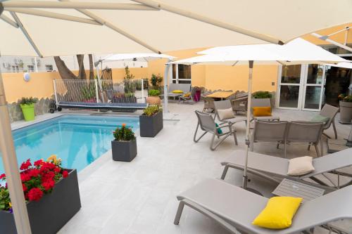 a patio with chairs and umbrellas and a pool at Hôtel A casa di Maria Cicilia in Ghisonaccia