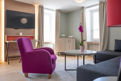 a living room with a purple chair and a table at Hotel Rosatsch in Pontresina