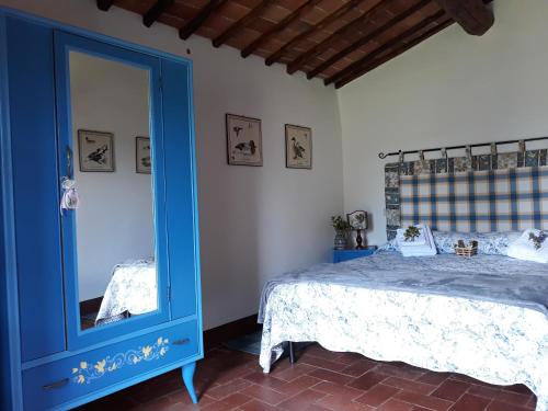 a bedroom with a blue bed and a mirror at Agriturismo Piemaggino in Castellina in Chianti
