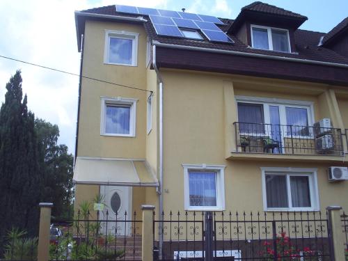 une maison jaune avec des panneaux solaires sur le toit dans l'établissement Harmatcsepp Apartmanház, à Nyíregyháza