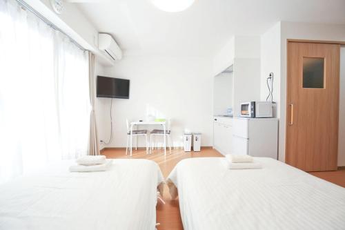 大阪市にあるConnect Innのベッド2台とテーブルのある白い部屋