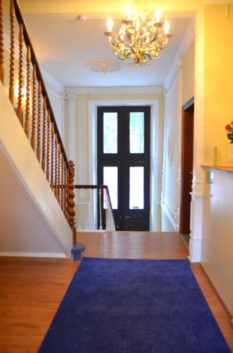 a hallway with a blue carpet and a chandelier at Hotel Villa Kisseleff in Bad Homburg vor der Höhe