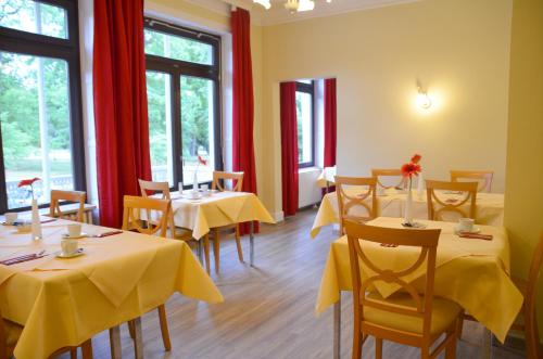 ein Restaurant mit Tischen und Stühlen mit gelbem Tischtuch in der Unterkunft Hotel Villa Kisseleff in Bad Homburg vor der Höhe