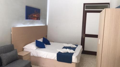 a bedroom with a bed with blue pillows and a chair at Le Malte House St. Julians in St Julian's