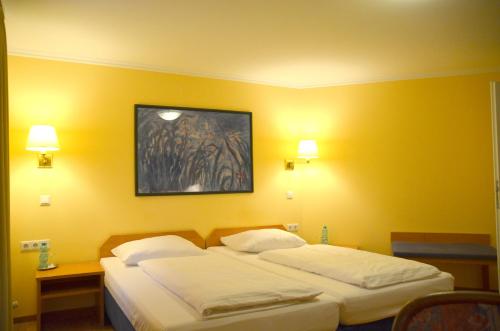 two beds in a hotel room with yellow walls at Hotel Villa Kisseleff in Bad Homburg vor der Höhe