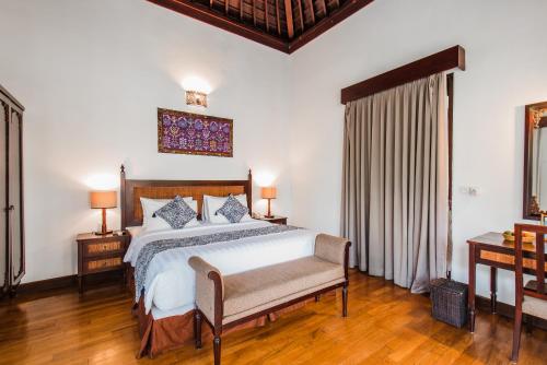 a bedroom with a bed and two tables and a window at Aldeoz Grand Kancana Villas Resort Bali in Kerobokan
