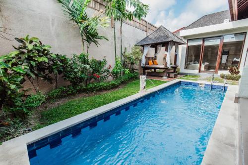 a swimming pool in front of a house at Aldeoz Grand Kancana Villas Resort Bali in Kerobokan