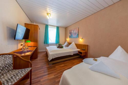 a hotel room with two beds and a tv at Landhotel Zum Niestetal in Kassel