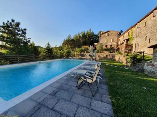 a swimming pool with two chairs next to a house at B&B Monte Splendore in Pietralunga