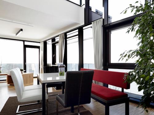 ein Wohnzimmer mit einem Tisch, Stühlen und Fenstern in der Unterkunft Thurnbach - Top Level Apartments in Aschau