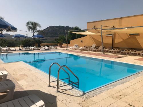 a pool at a hotel with chairs and umbrellas at Baglio Pocoroba in Calatafimi