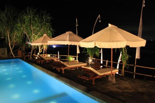 a swimming pool with umbrellas and lounge chairs next to a swimming pool at Twilight Ceningan in Nusa Lembongan