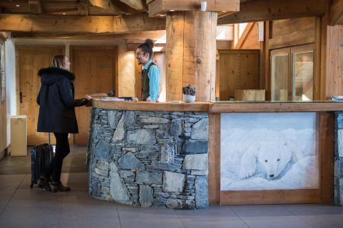 two people standing at a bar with a polar bear on it at CGH Résidences & Spas Le Village De Lessy in Le Grand-Bornand