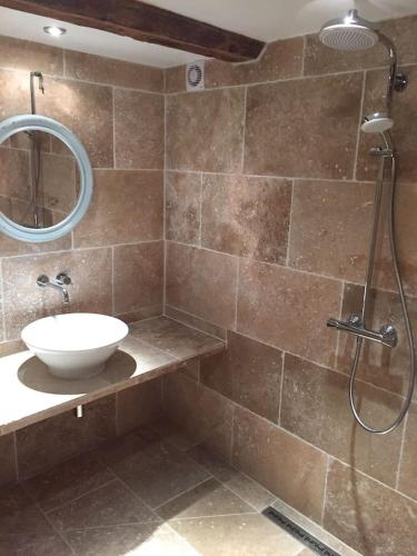 une salle de bain avec un lavabo et une douche avec un miroir dans l'établissement La Magnanerie, à Bonnieux