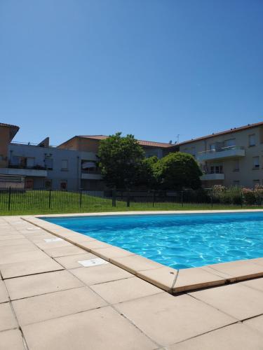 une piscine avec de l'eau bleue devant un immeuble dans l'établissement T3 Bonnefoy, à Toulouse