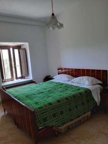 a bedroom with a large bed with a green blanket at Casa Iacobucci in Fagnano Alto