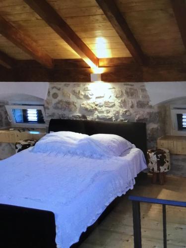 a bed in a room with a stone wall at Stein Haus in Pirovac