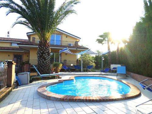 a swimming pool with a palm tree in front of a house at Bed and Breakfast Villa Algi in Corropoli